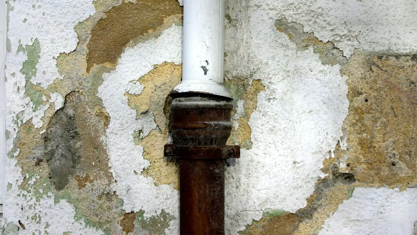 Peeling, stained wall around a corroded pipe